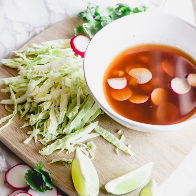 bowl of pozole rojo with garnishes